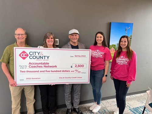 City & County Credit Union holding check in pink shirts